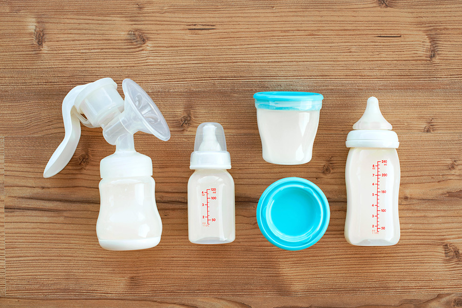 Vignette of handheld breastpump and bottles against wooden background