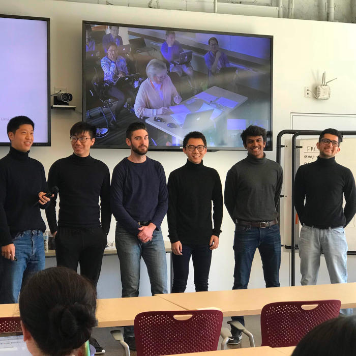 6 students standing at the front of the classroom during a presentation.