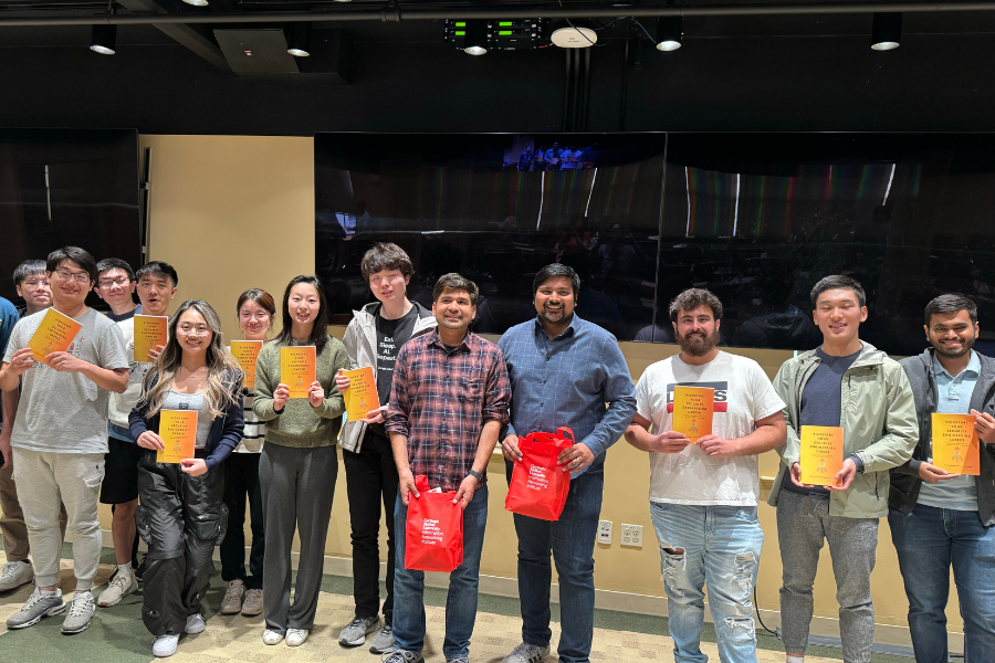 Students standing with alumni with copies of a book in their hands