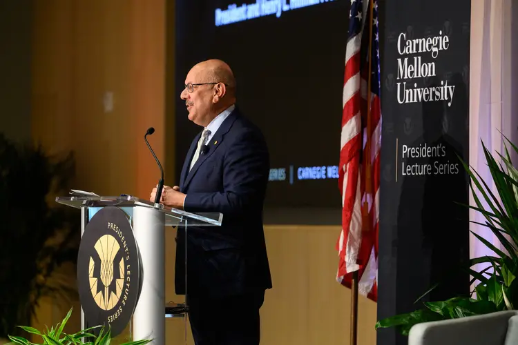 President Jahanian at podium with American flag behind him