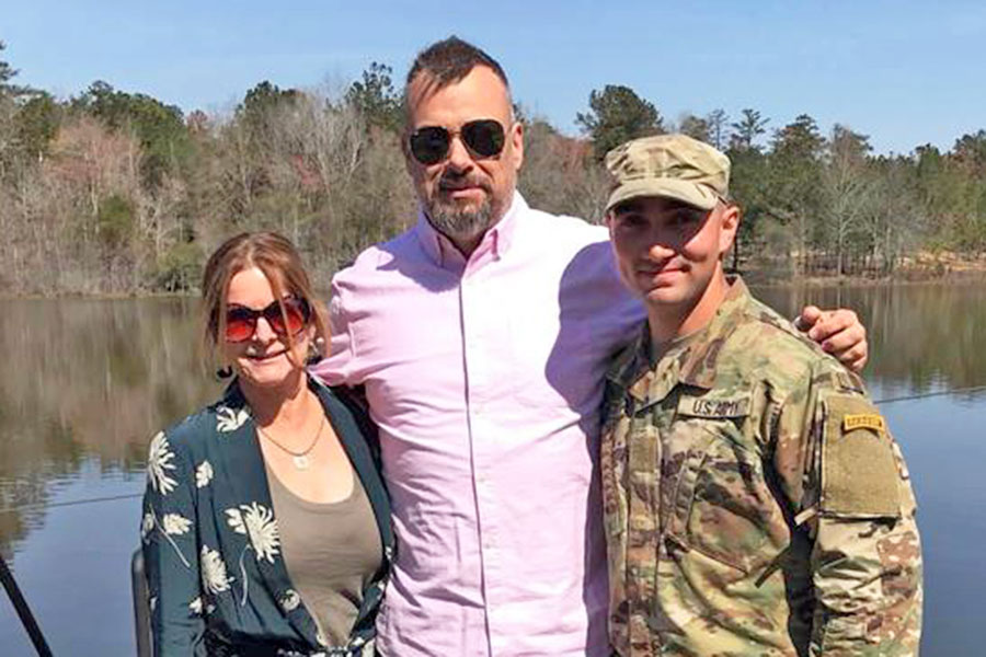 travis with a woman and a man standing in front of a pond smiling at camera with sun in their eyes