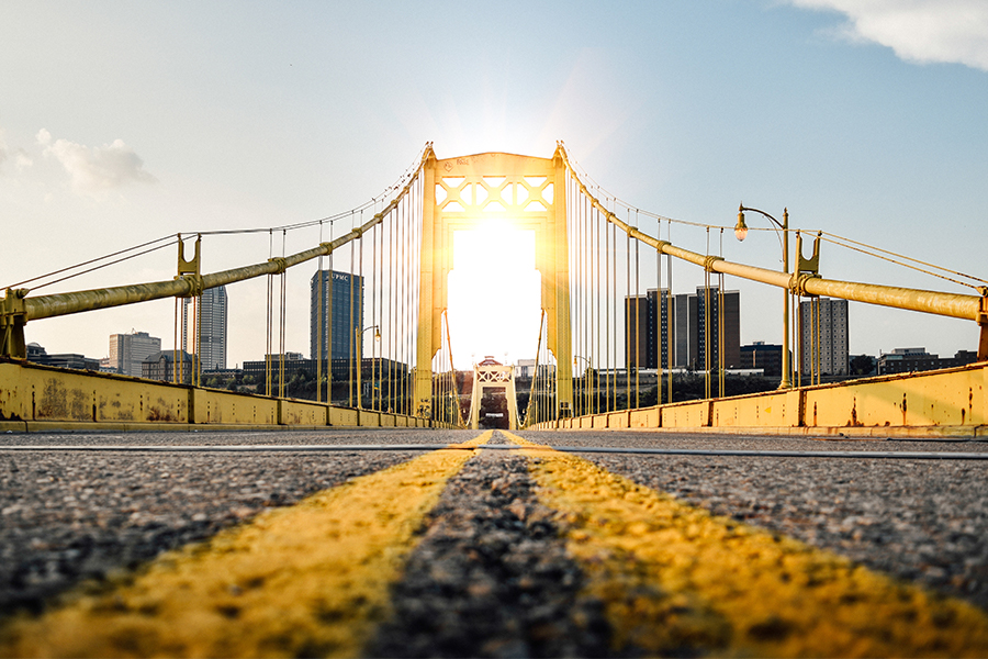the sun shining through a yellow bridge in Pittsburgh