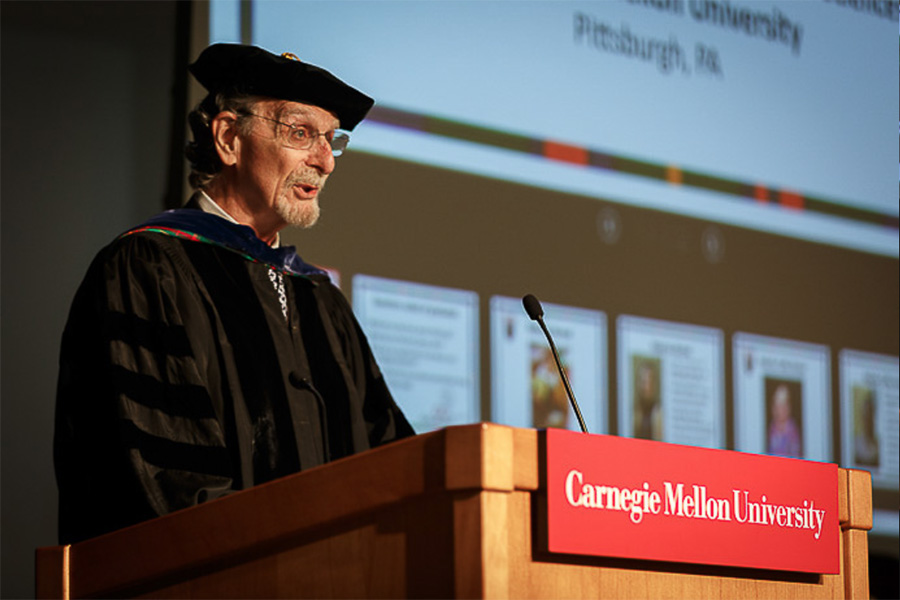 Klahr speaking from a podium at graduation