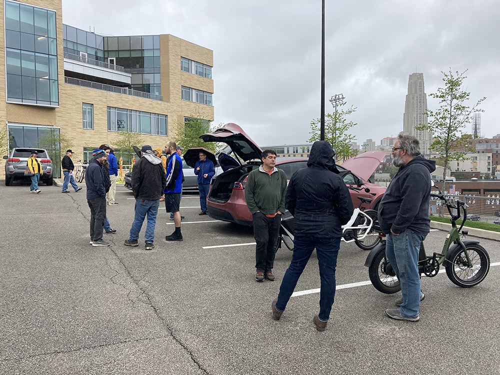 EVs on display in parking lot with attendees standing around