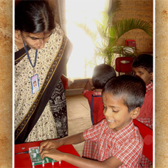 A teacher assists a student at the Mathru School in using the newest version of the Braille Writing Tutor.