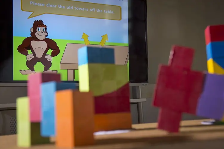 Colorful blocks on a table in front of a screen with an animated gorilla.