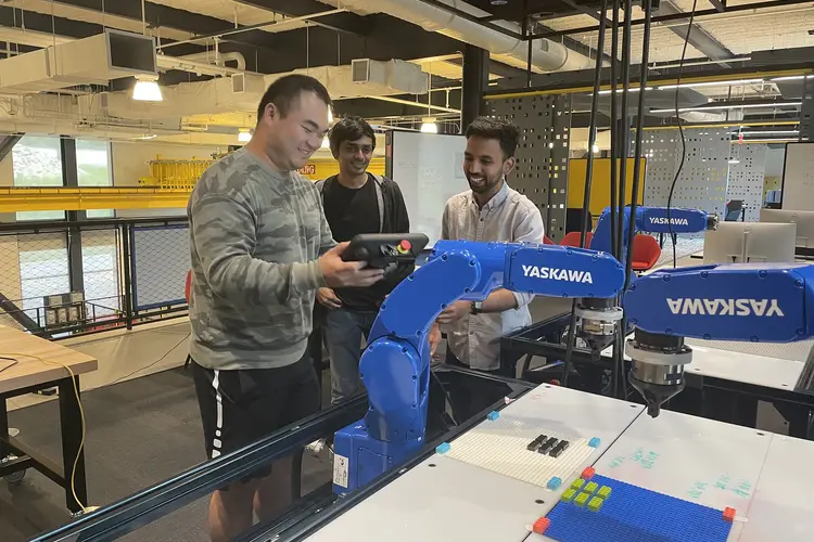 three people in lab standing around robotic arm