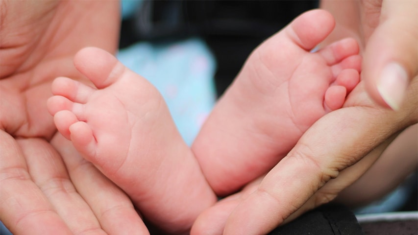 Image of the feet of a baby and hands of a mother