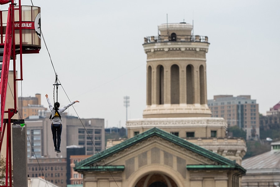 image of a person riding the zip line with Hamerschlag Tower in view