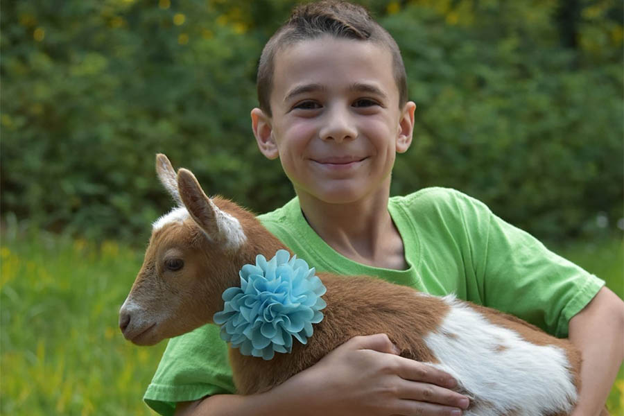boy smiling holding goat in his arms