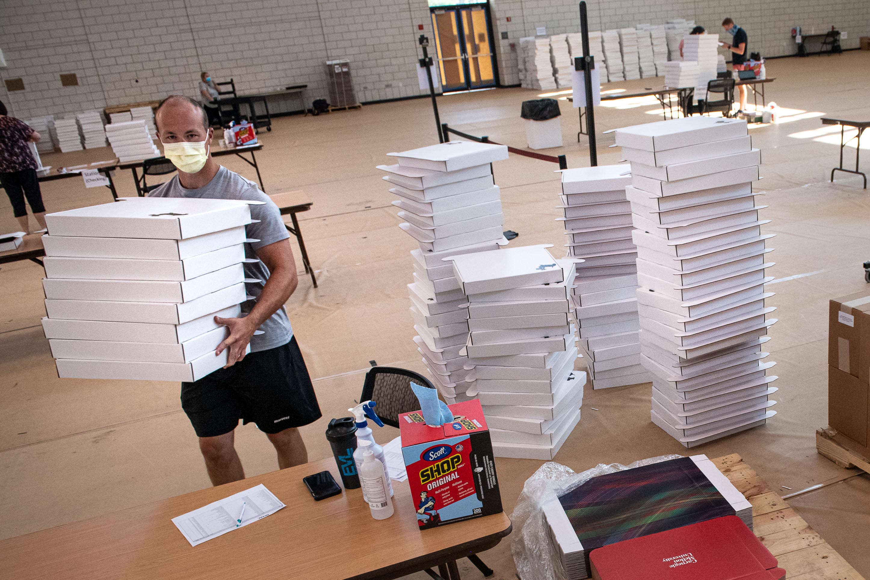 Image of Matt McCamley carrying stack of flat white boxes