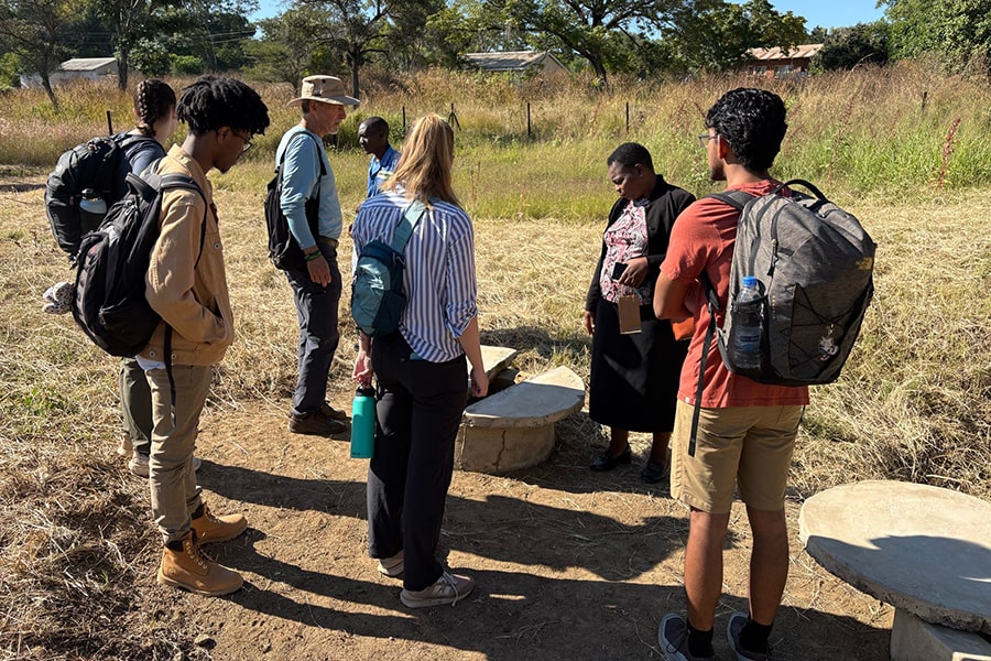 CMU students with community partners in a field looking at a well on an engineers without borders trip
