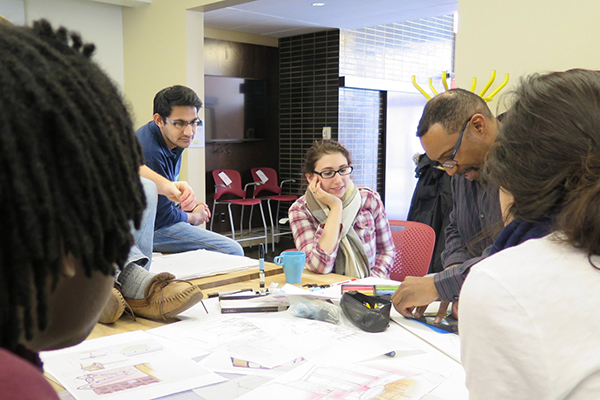 photo of students engaging with a professor around a table