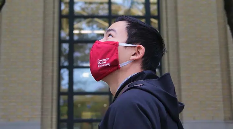 CMU student looking up to sky wearing CMU branded mask