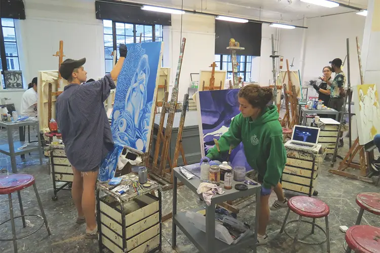 Art students painting on canvases set in a studio.