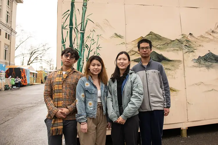 Members of the CMU's Chinese Student Association standing on the street in front of a bamboo and mountains mural.