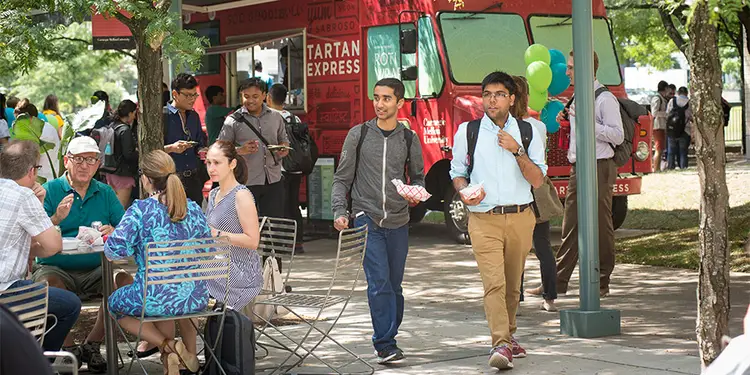 Students eating outside in a courtyard, near the Tartan Express food truck.