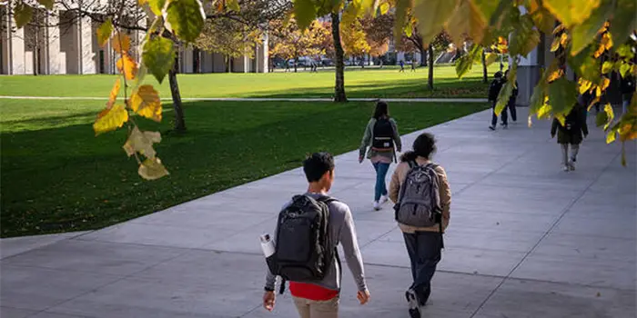 Students walking across campus in autumn.