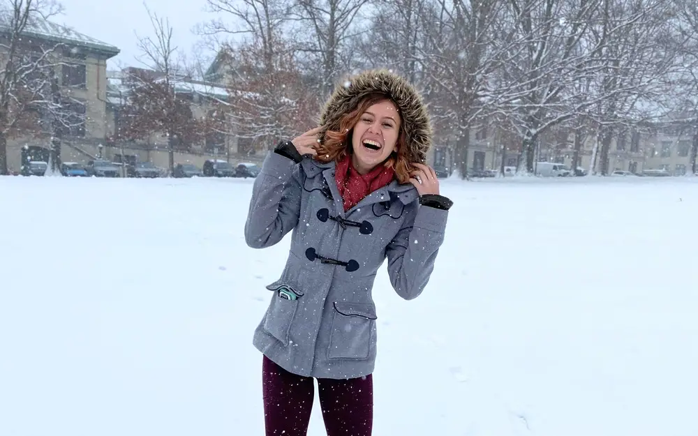 Student smiling on campus outside on a snowy day.