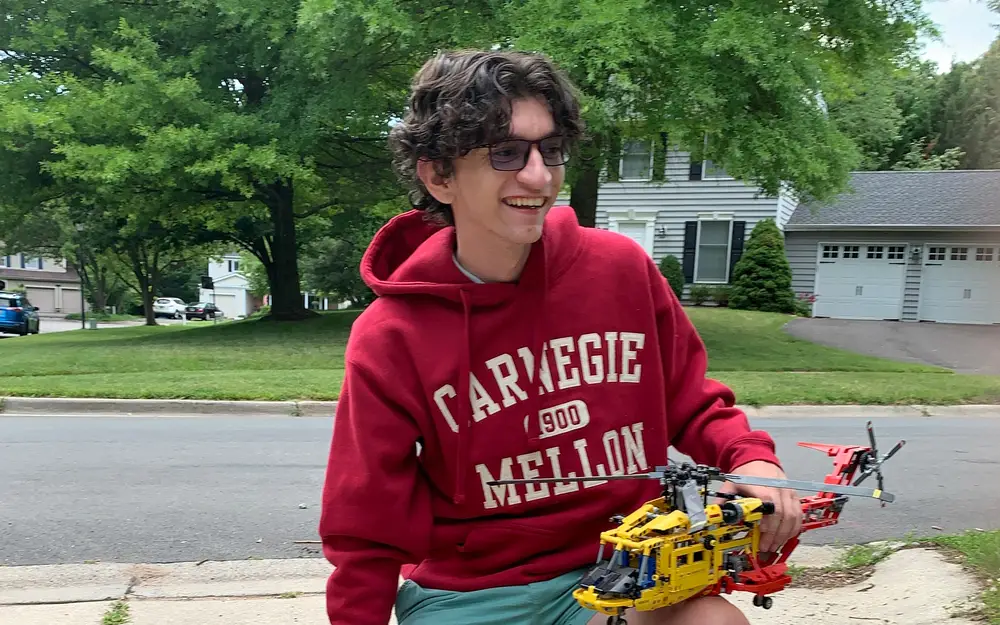 Student smiling while holding remote helicopter.