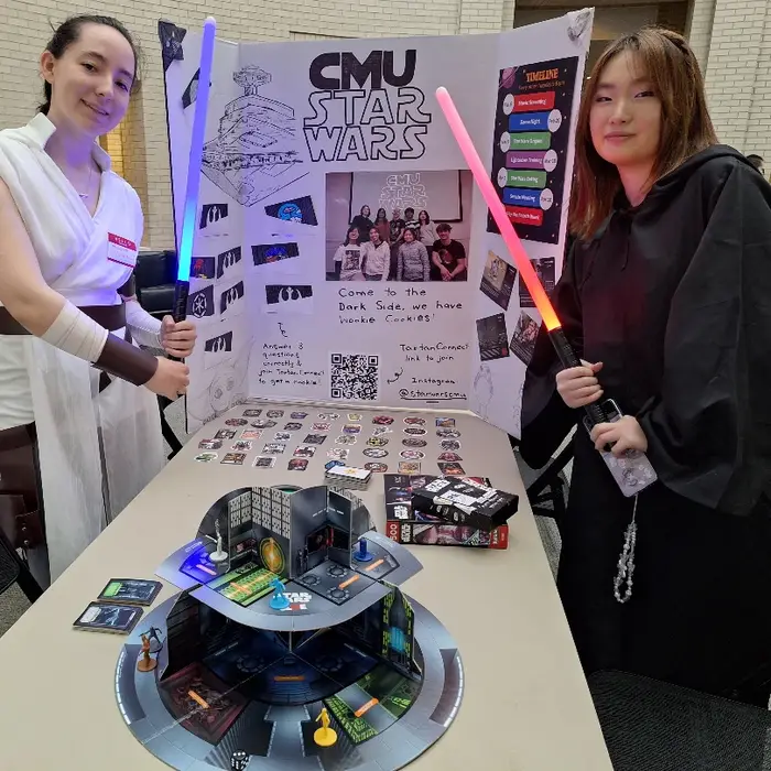 Maile and friend pose in front of a Star Wars Club poster