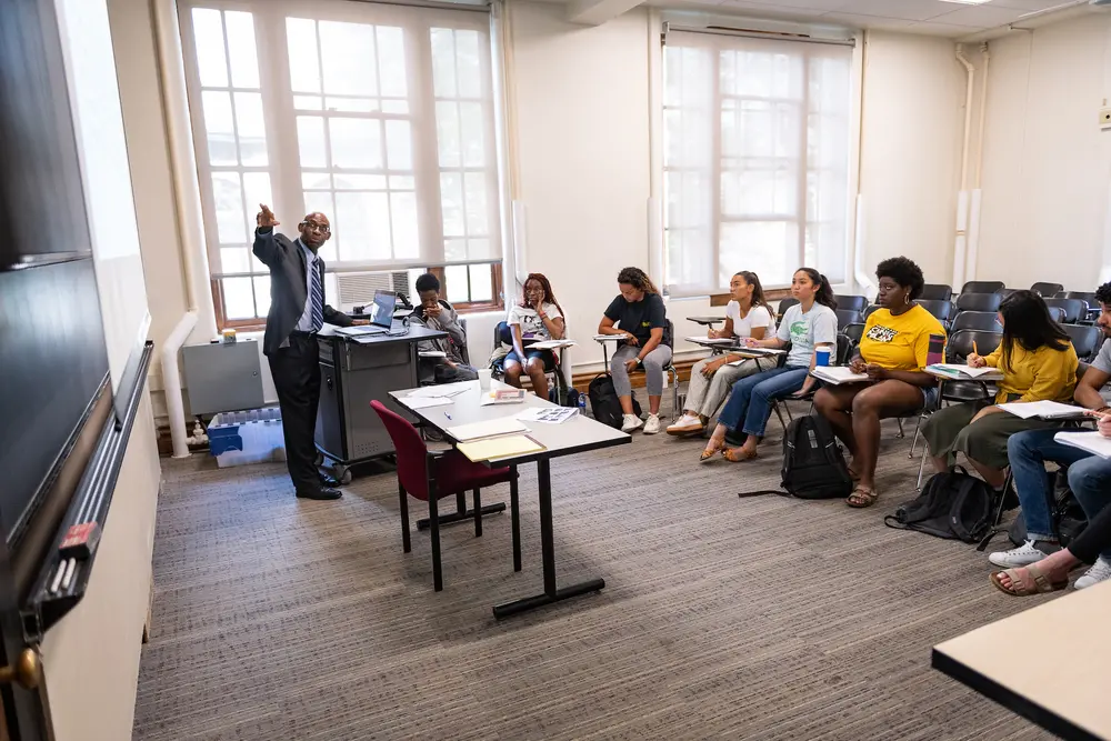 Students looking at a blackboard as professor Joe Trotter points toward it in a lecture.