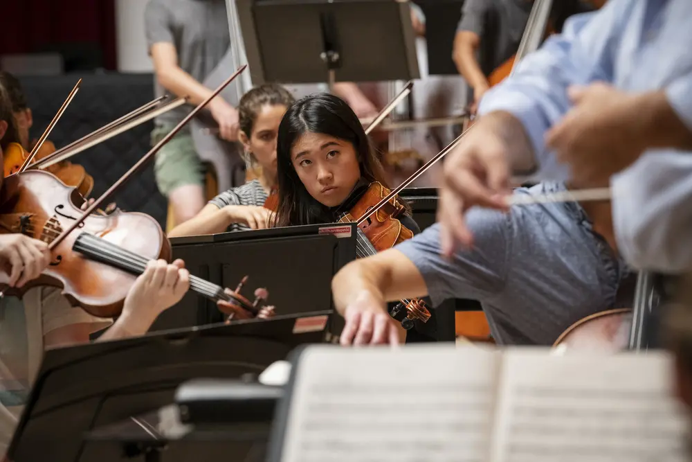 Violin student closely watching conductor and professor Andres Cardenes.