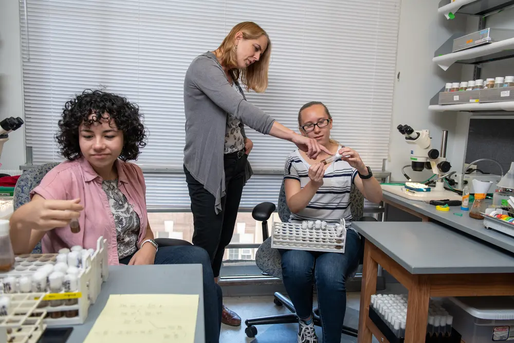 Professor pointing at a test tube that a student is holding.