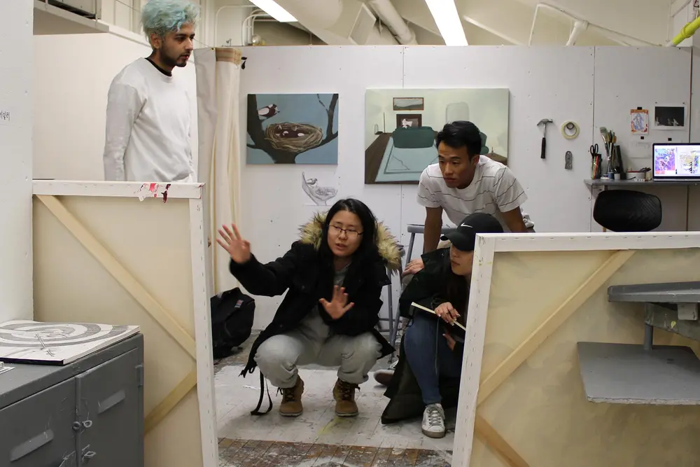 Students looking at their artwork, propped up on canvases in their studio space.