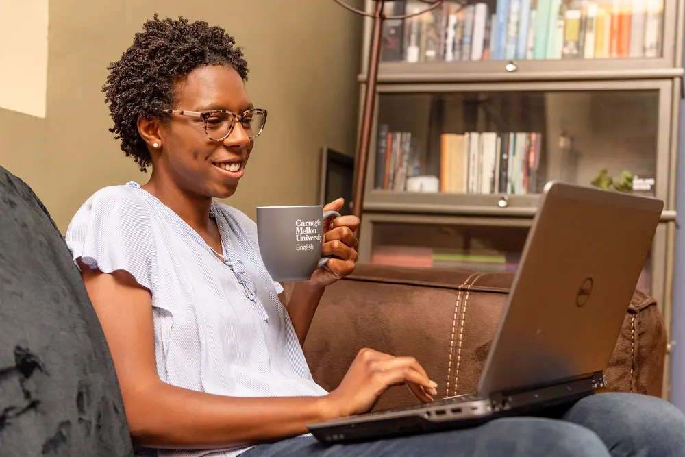 English student smiling while working on laptop