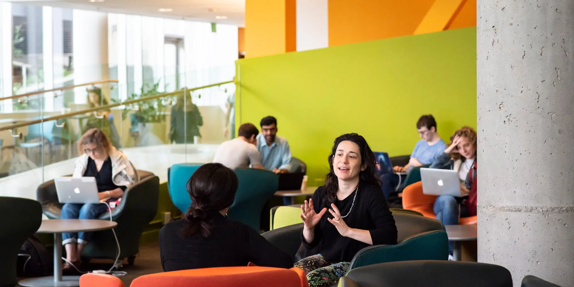 Students talking and working in a brightly-colored common area.