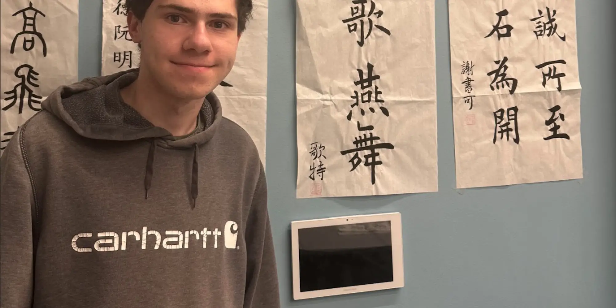 A photo of Peter standing in front of Chinese calligraphy posters.