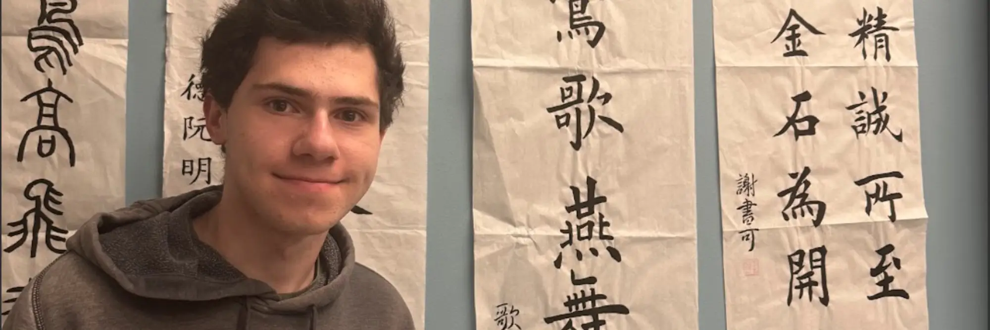 Peter standing in front of Chinese calligraphy posters