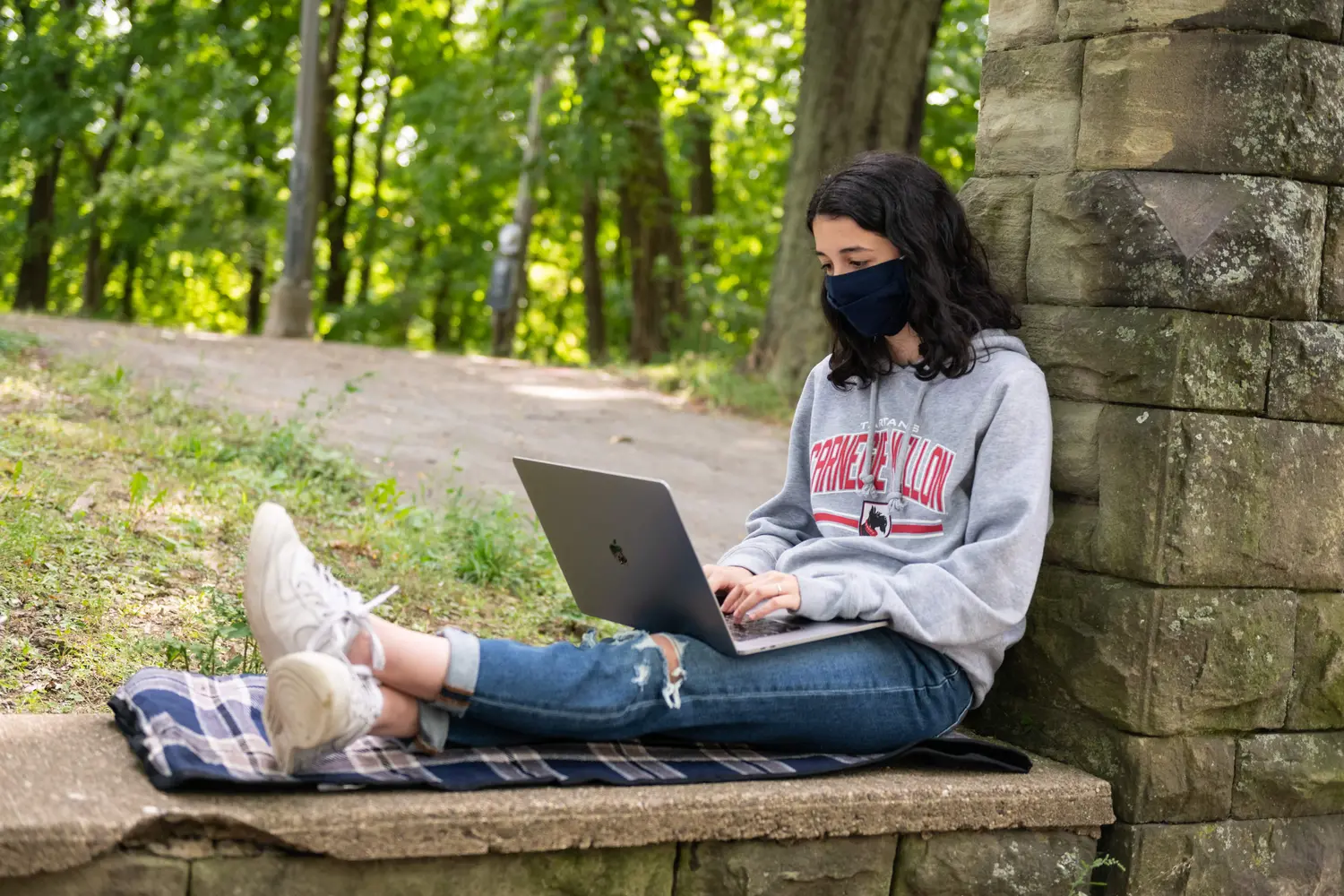 student on her laptop outside with mask