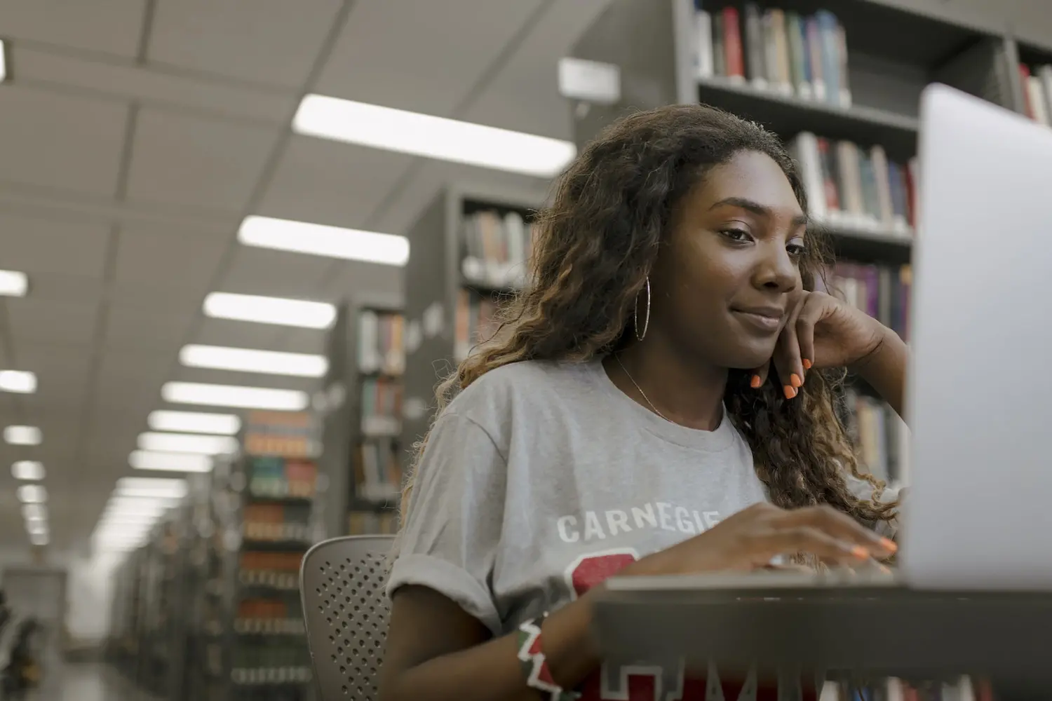 CMU student in library smiling and looking at her computer