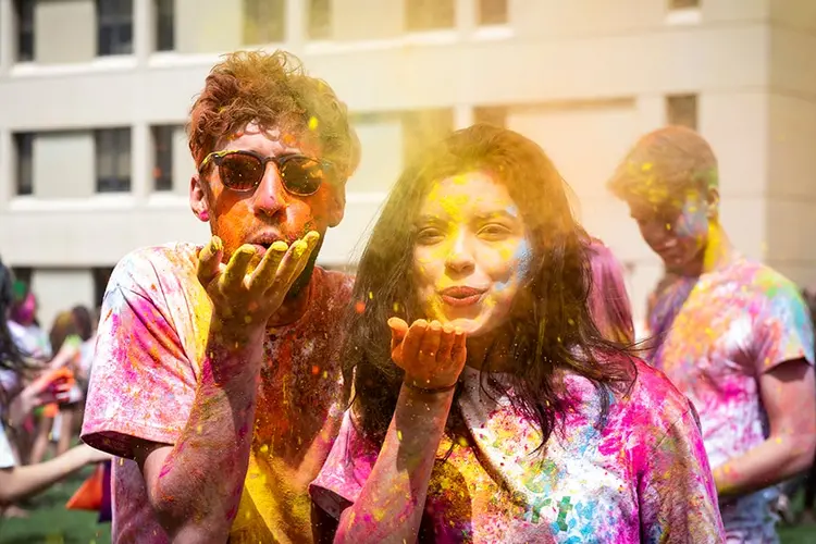 students blowing paint into the camera during Holi