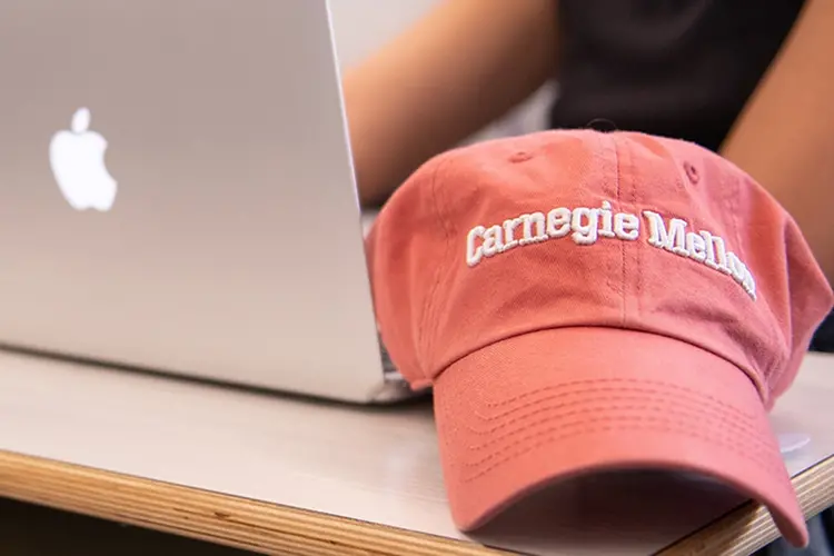 Close up of a student's laptop and Carnegie Mellon hat