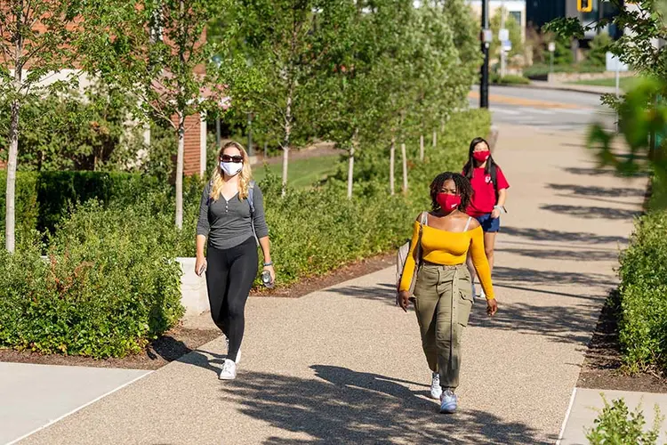 CMU students walk on campus outside wearing masks