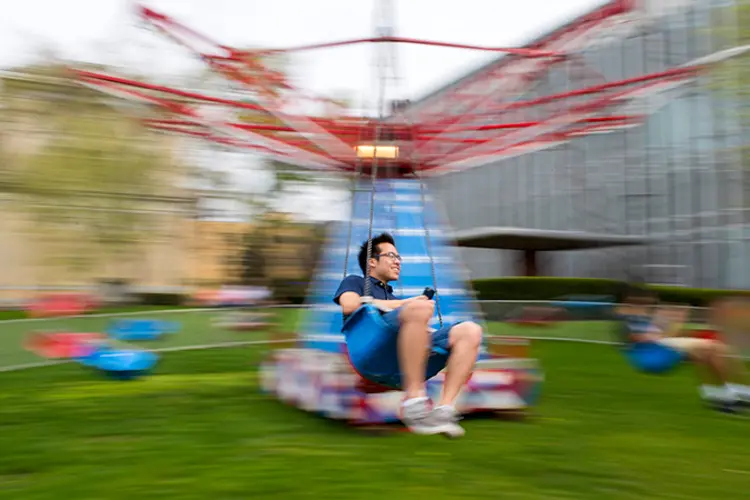 A student swinging from a carnival ride on Campus.