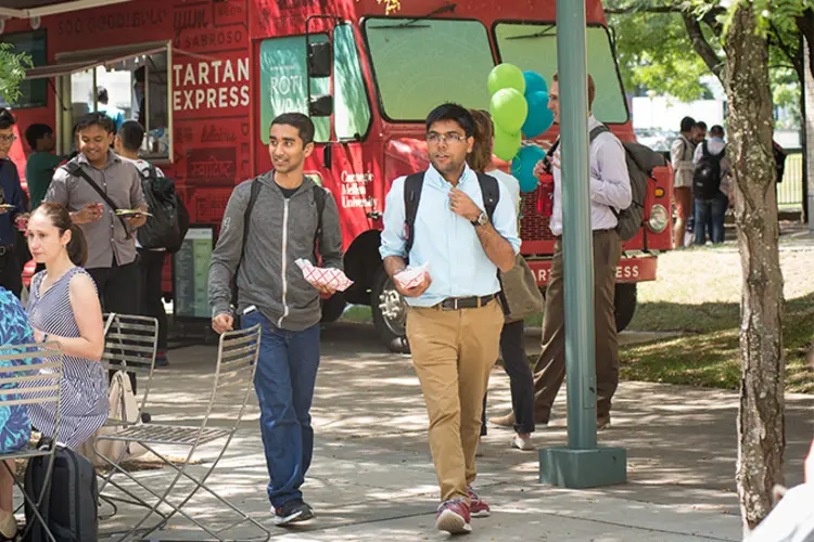 Students eating outside in a courtyard, near the Tartan Express food truck.