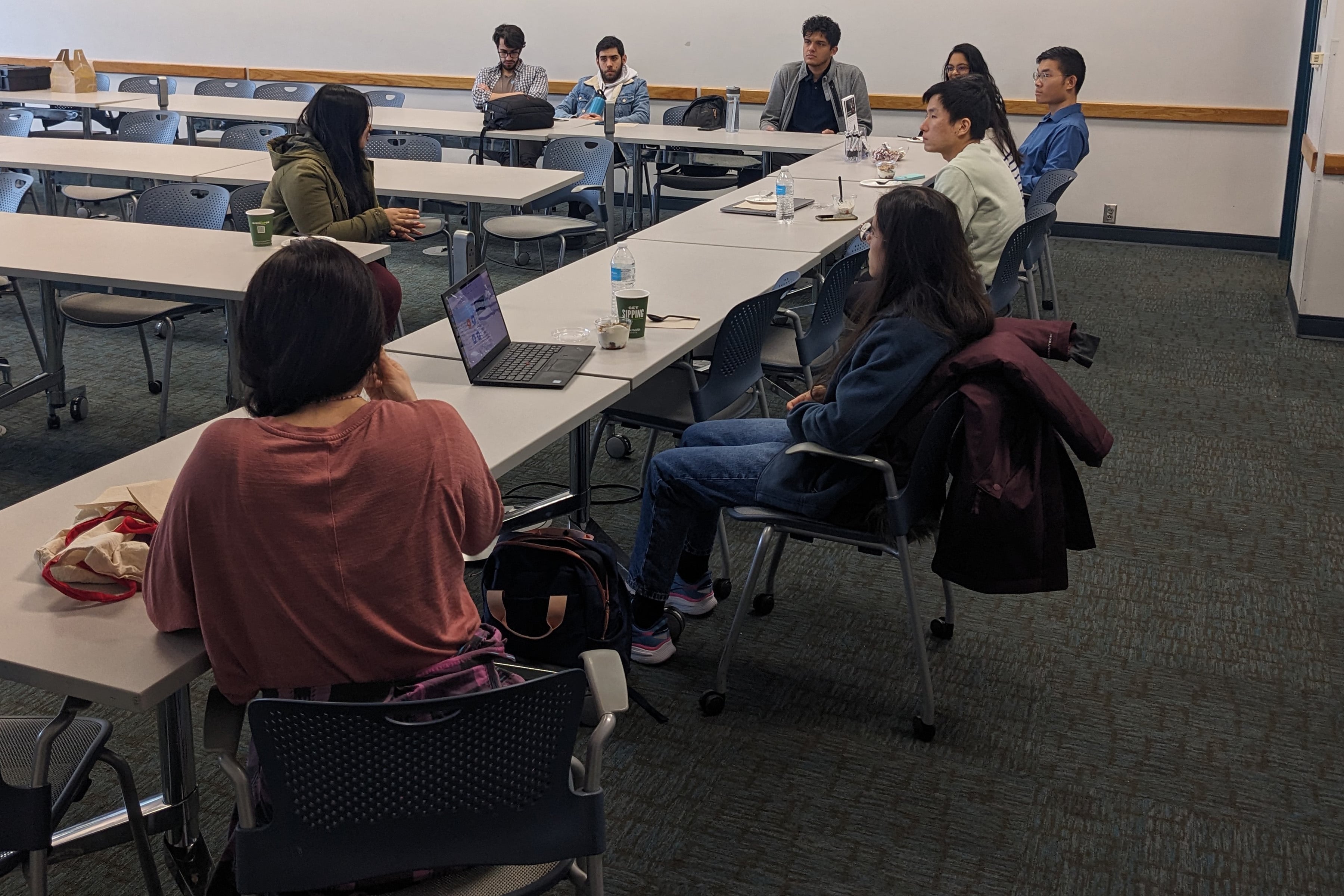 AI-SDM students at a social event, seated in a meeting room and having a group discussion