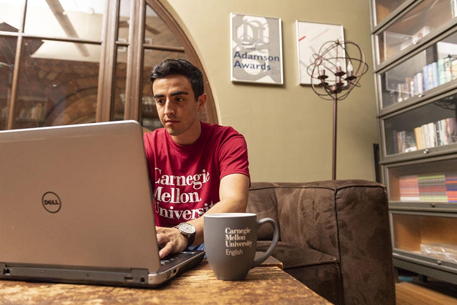 Student wearing a CMU shirt using a computer at home
