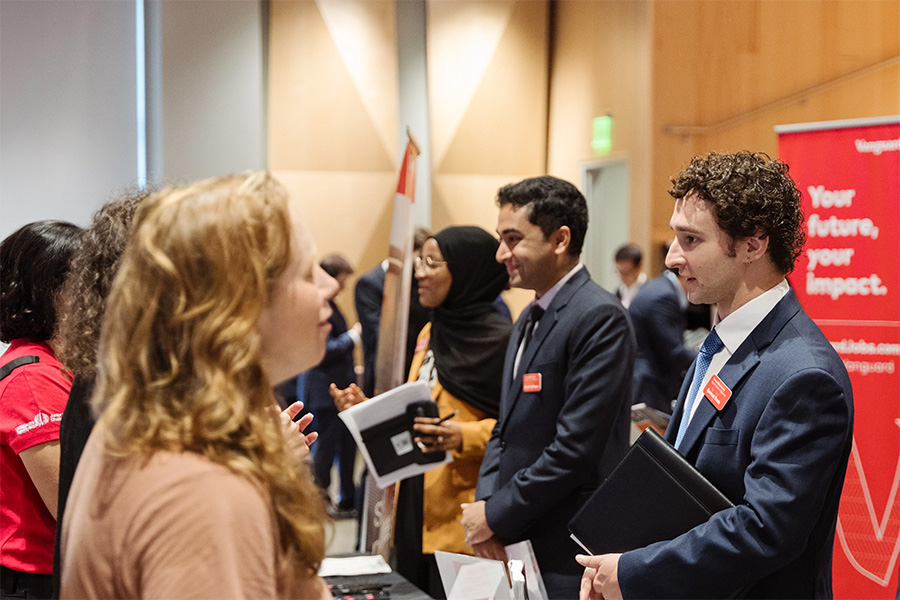 Students check in at a busy event registration table at a career fair.