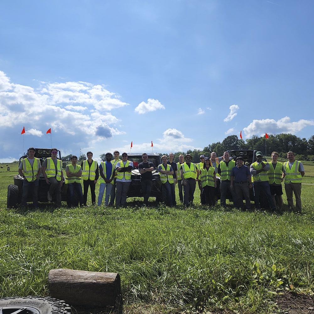 A large group photo in a field with ATVs