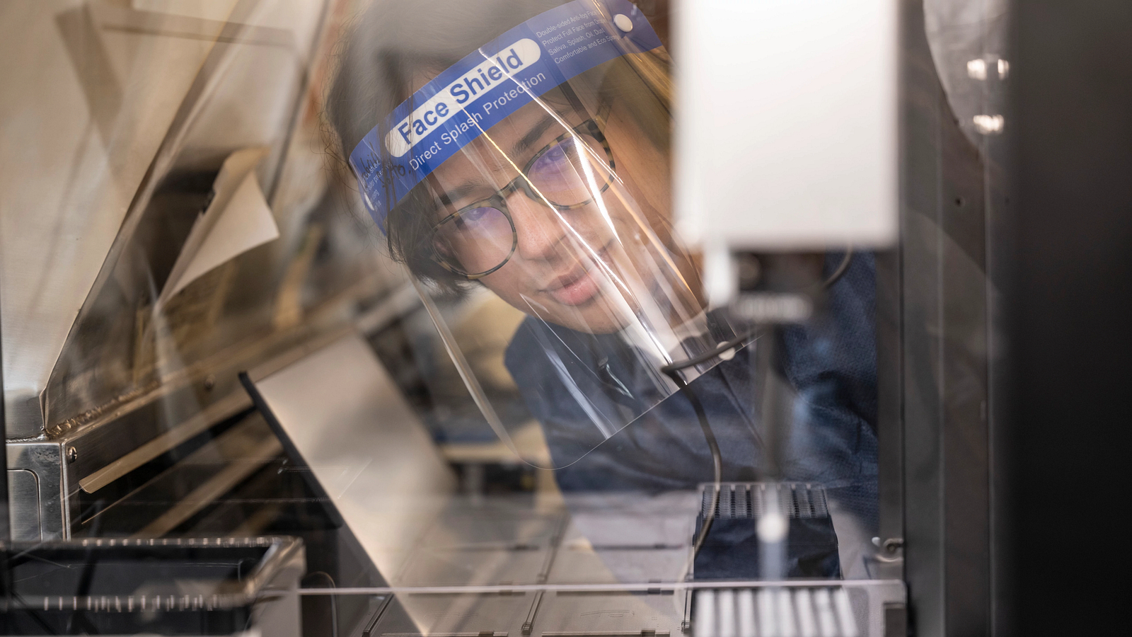 Student wearing a hood looking at experiment