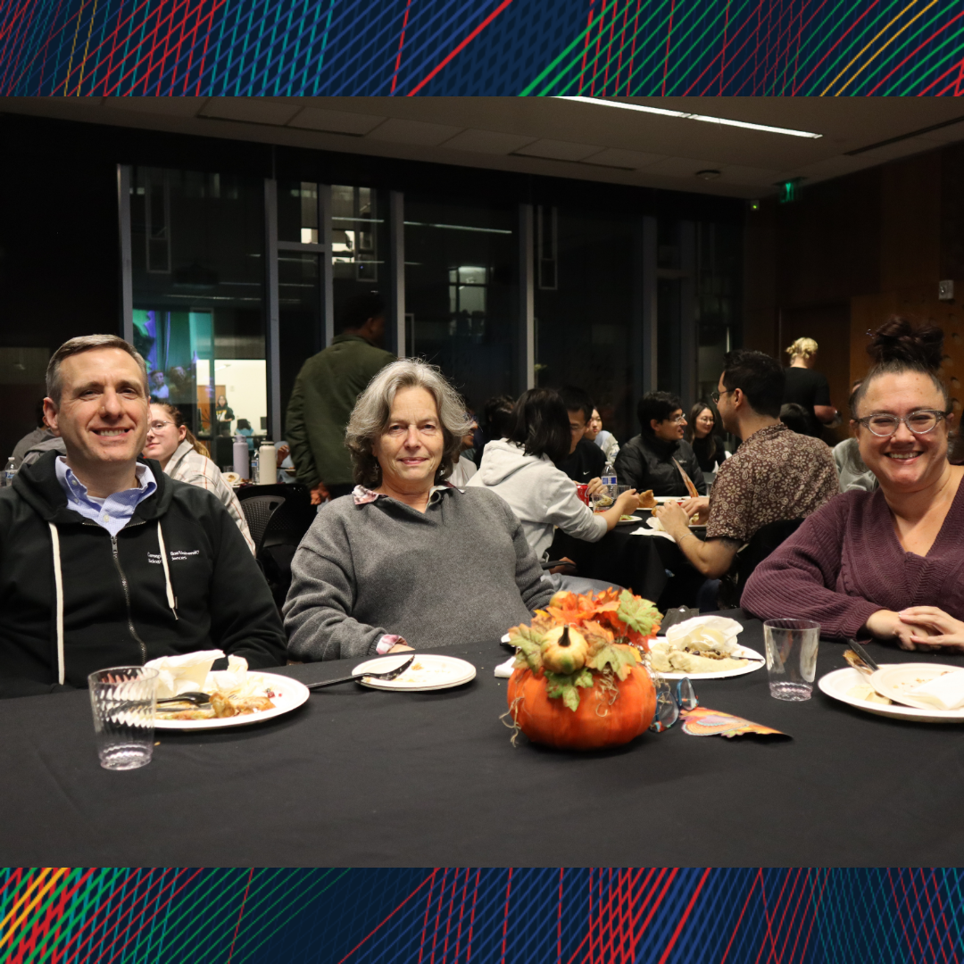 Three people smiling at the camera during dinner