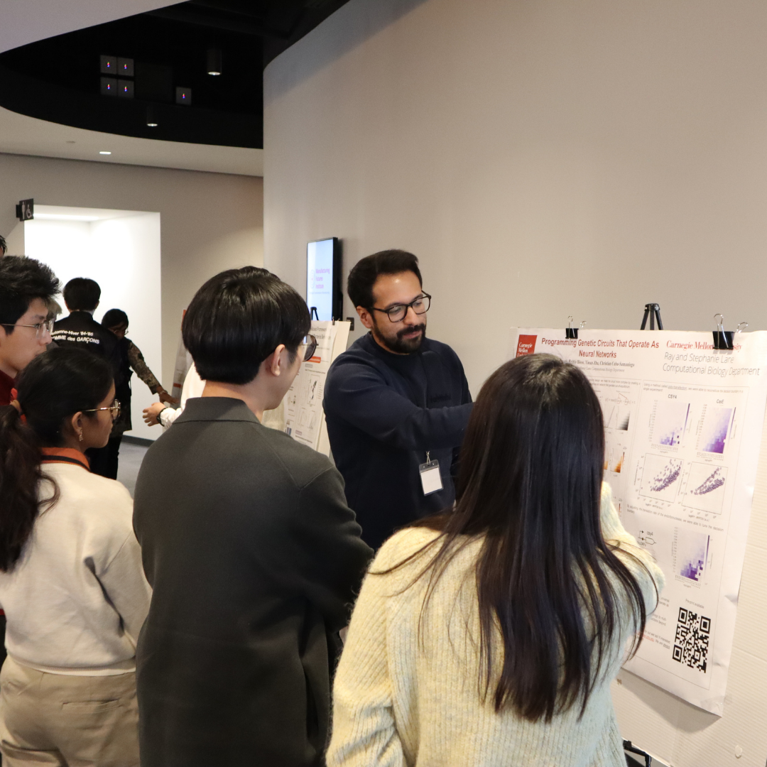 A man pointing at research poster in front of a group of people