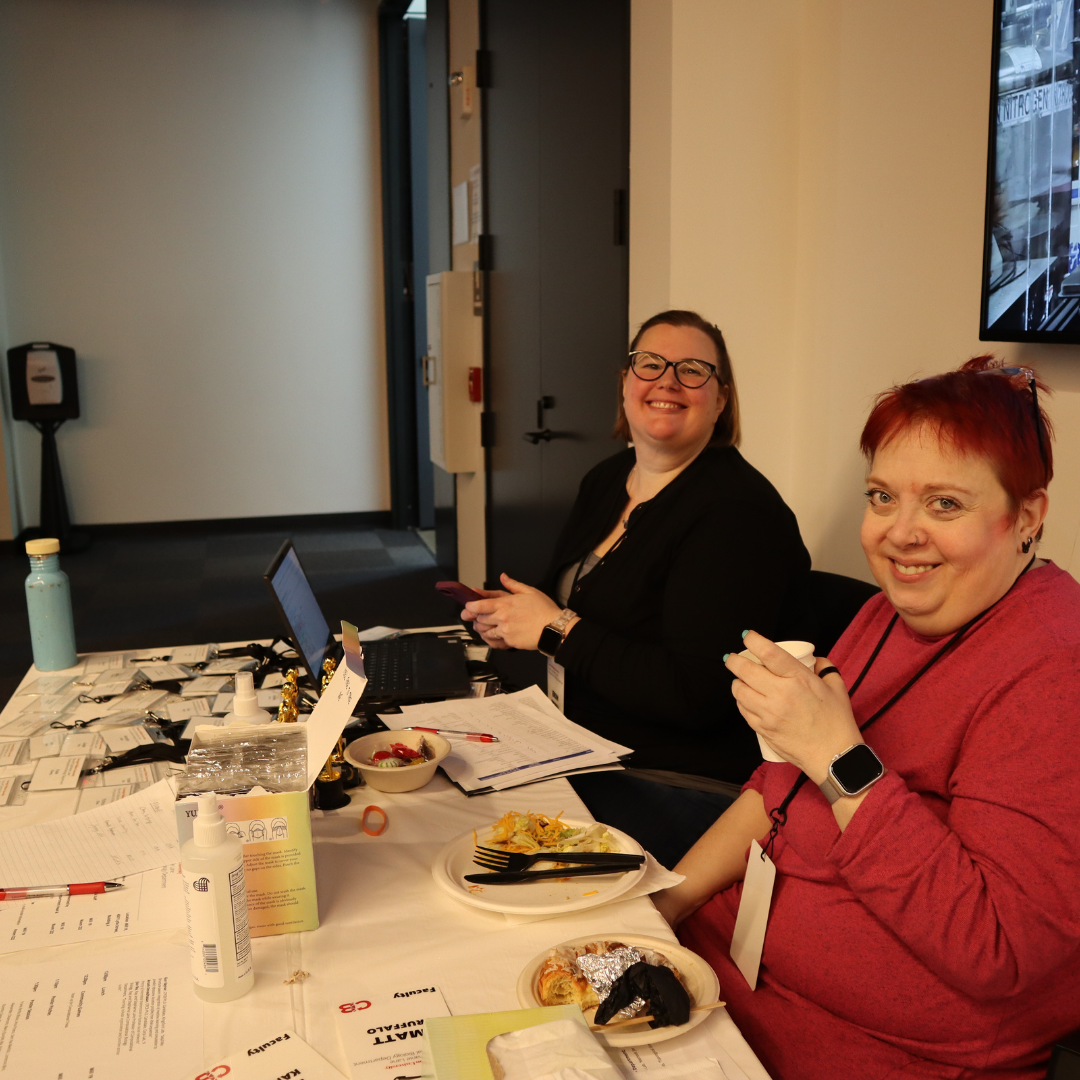 Two women smiling at the camera at the registration table