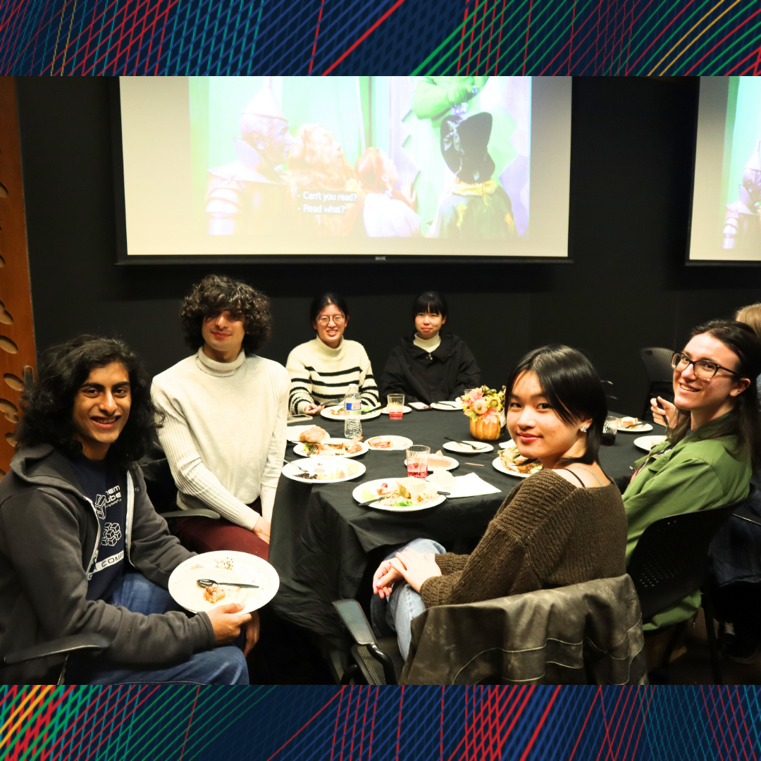 A group of people sitting at a table and smiling at the camera