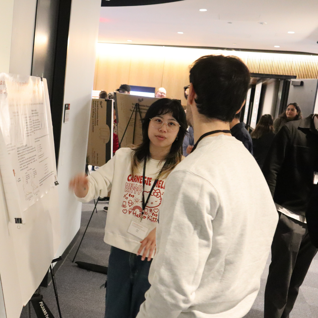 A woman talking to a man in front of a research poster
